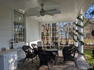 A picture of a white porch with black wicker furniture 