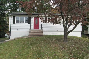 picture of a white bungalow with a red door